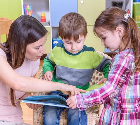Person reading a book to two children