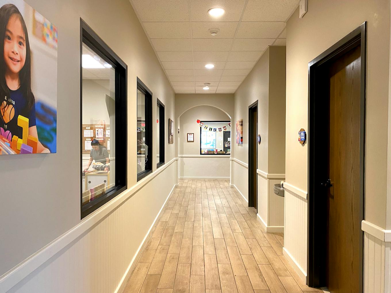 Hallway with wood-look flooring and interior windows looking into a room