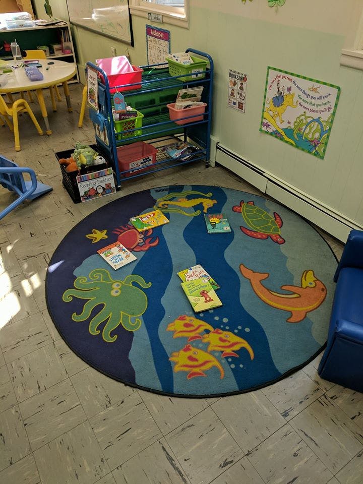 Books on a round rug with sea animal designs in a classroom
