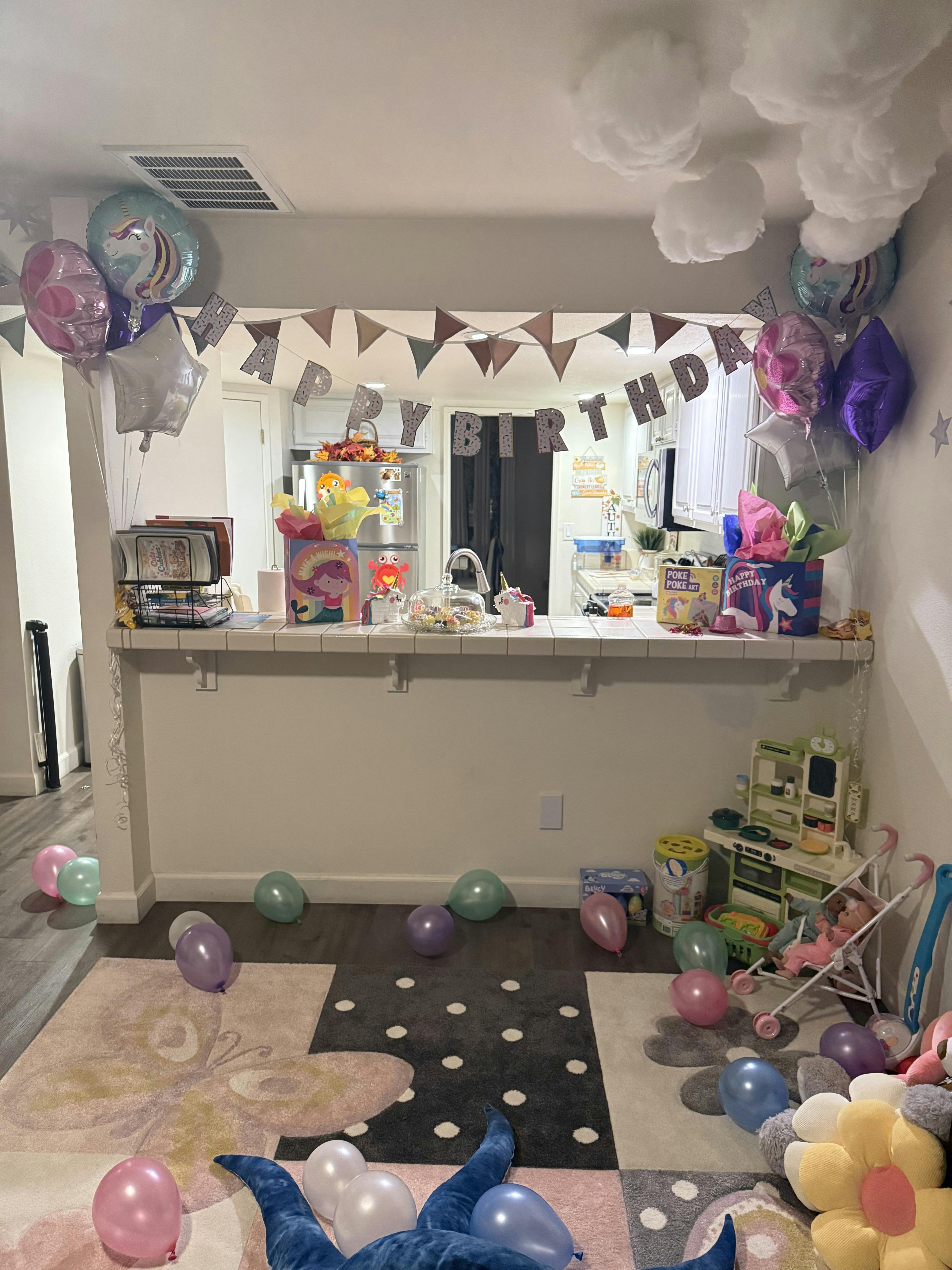 A room decorated for a birthday party with balloons, gifts, and a "Happy Birthday" banner