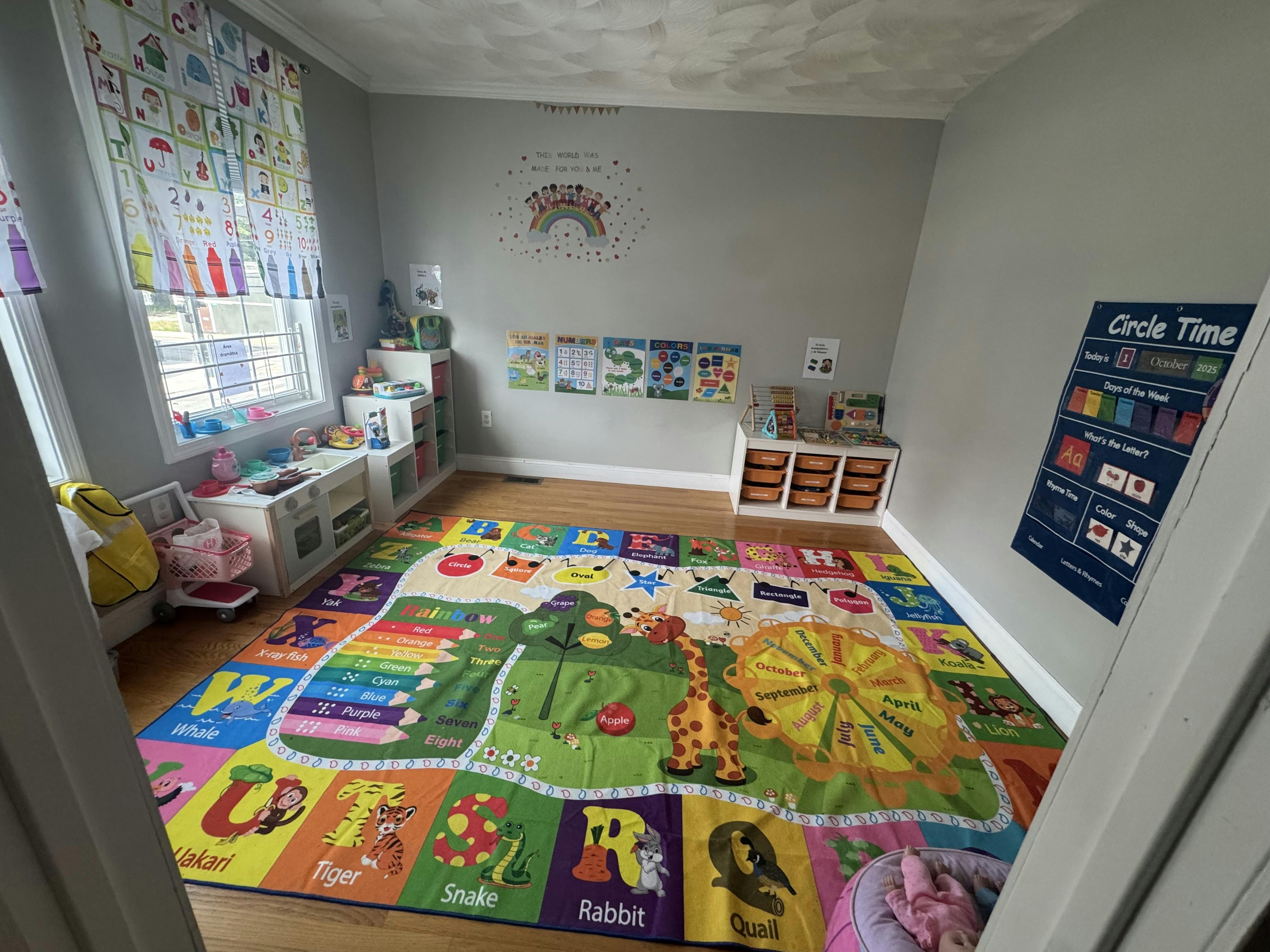 Child's playroom with an alphabet rug, toy kitchen, and learning charts on the wall