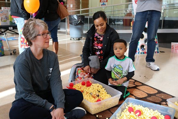 Person and child sitting on floor next to containers of popcorn