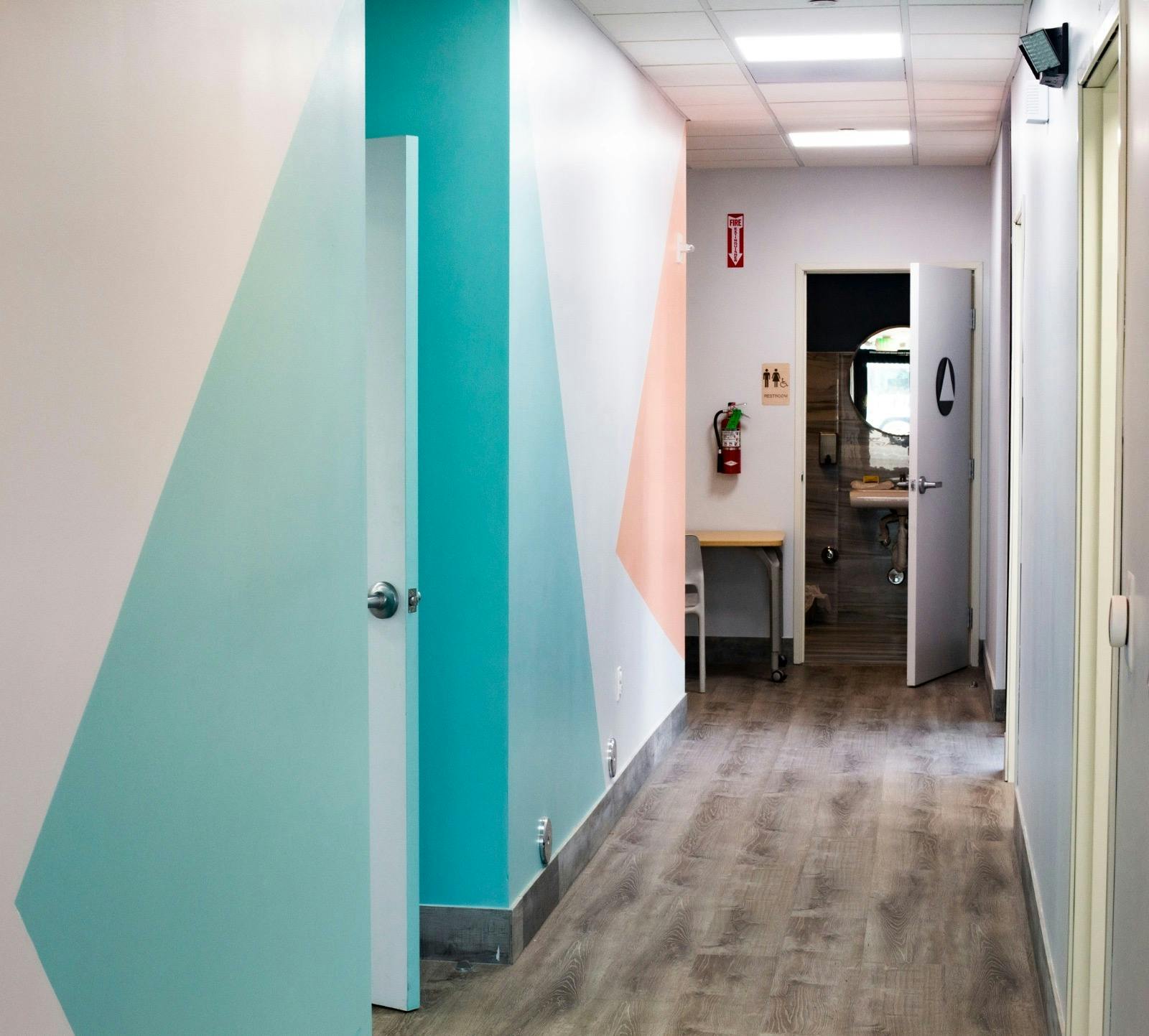 Hallway with geometric painted walls and an open door to a restroom