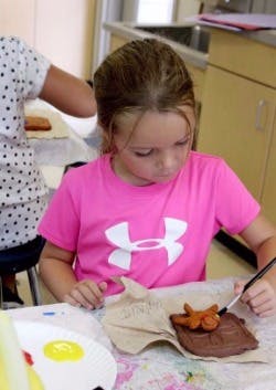 Child painting a clay sculpture
