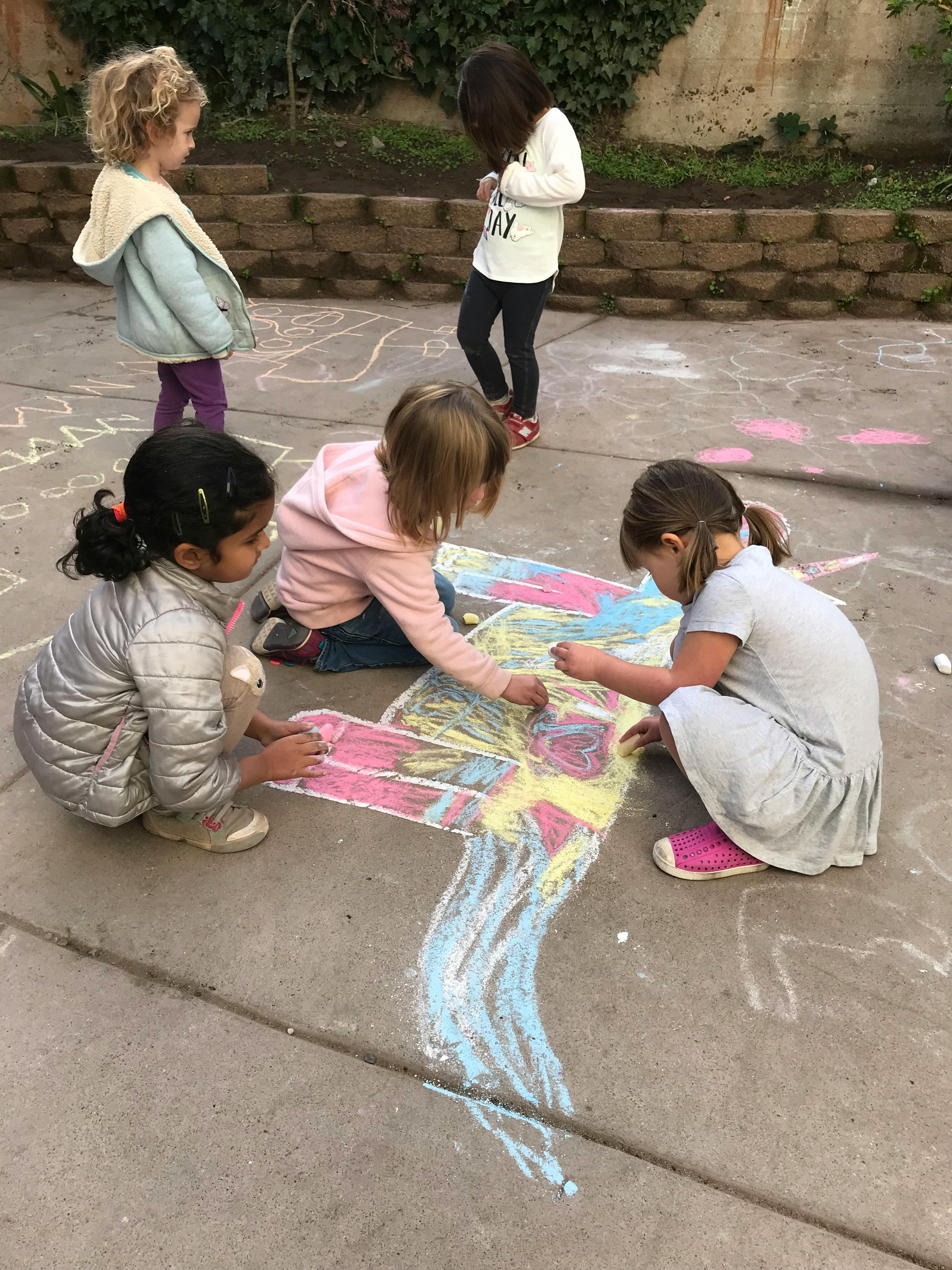 Children drawing with chalk on pavement