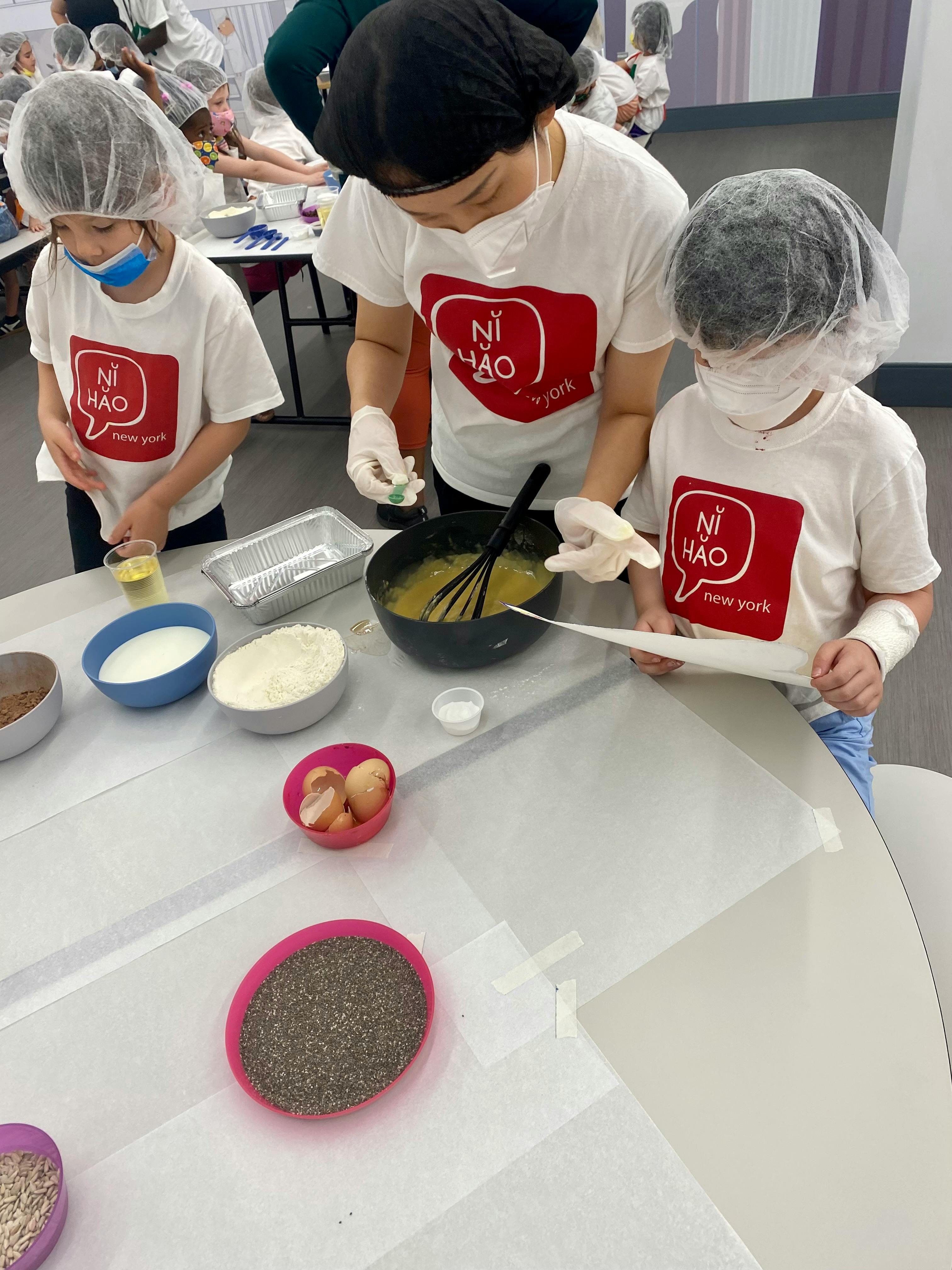 People in hairnets baking, one stirring a bowl, two others watching