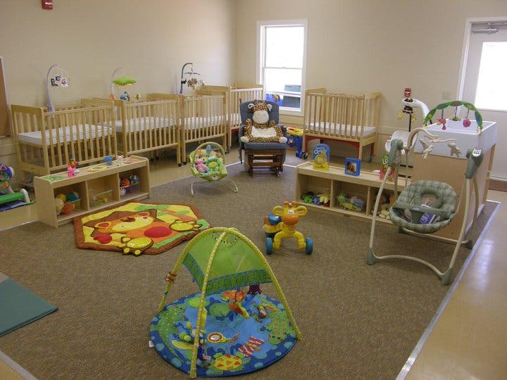 Nursery room with multiple cribs, play mats, and baby swings