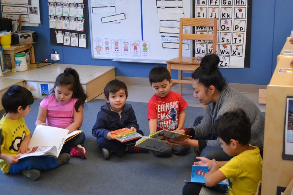 Adult reading to four children in a classroom