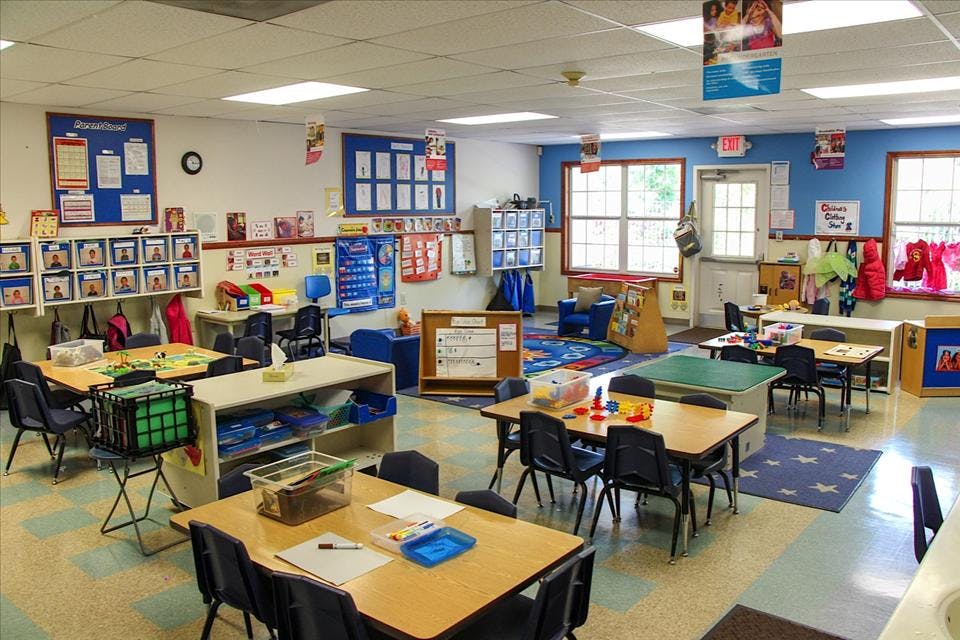 A colorful empty classroom with small tables, chairs, and learning materials