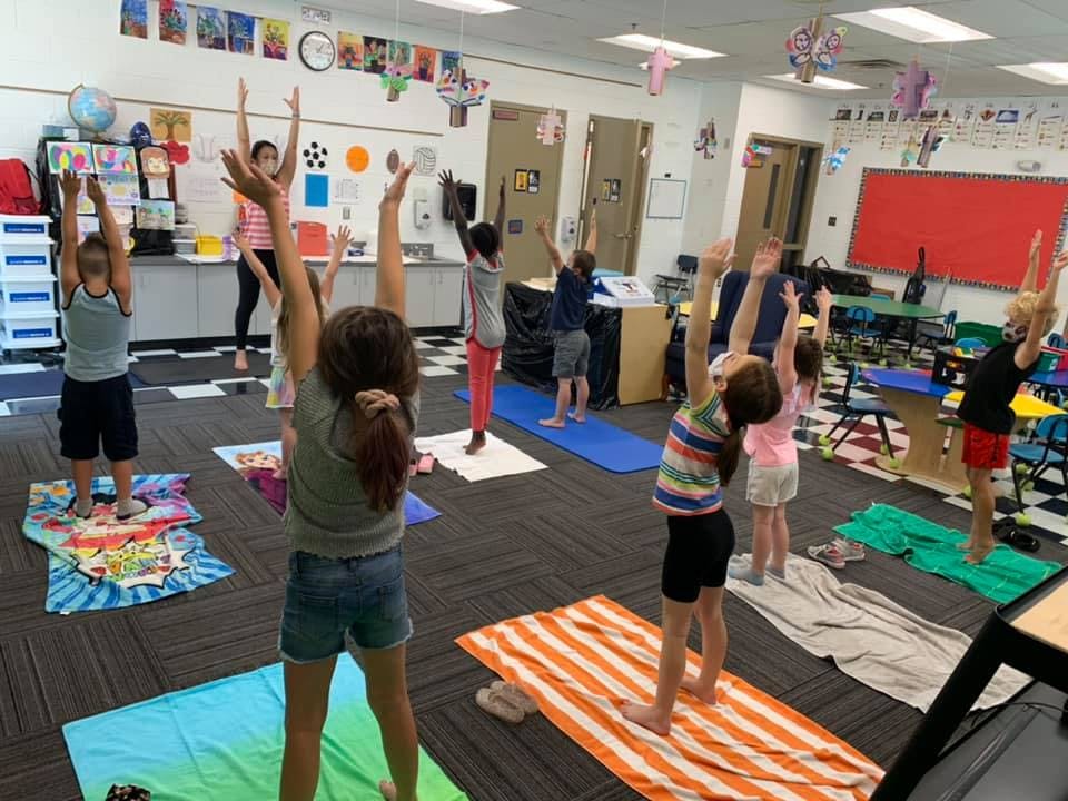 Children and adults doing yoga in a classroom