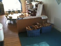 Classroom with tables, chairs, shelves, and storage bins