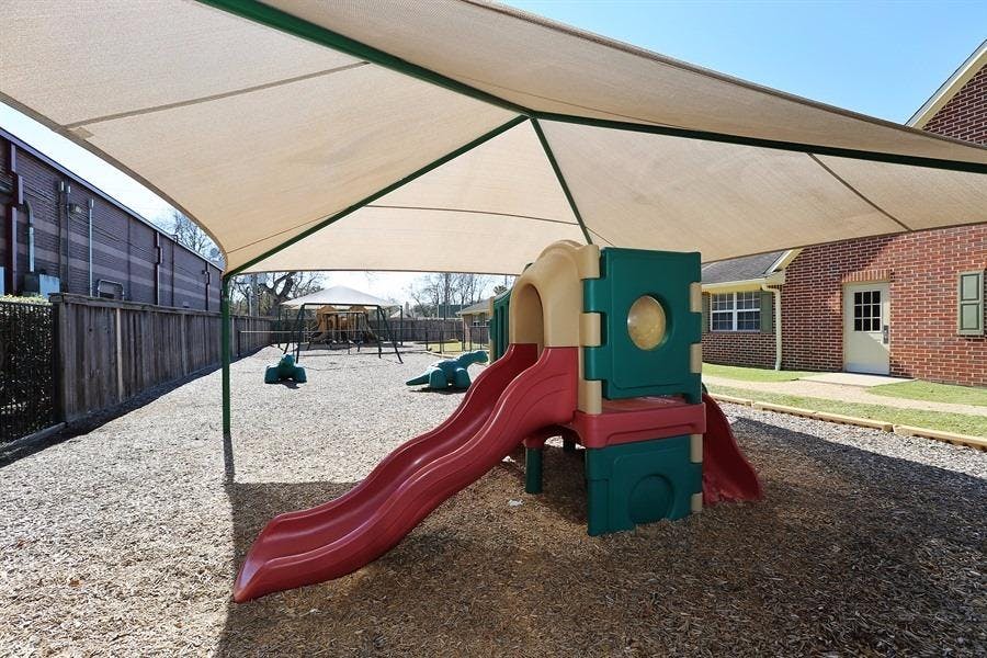 Playground with a slide and swings under a large shade canopy