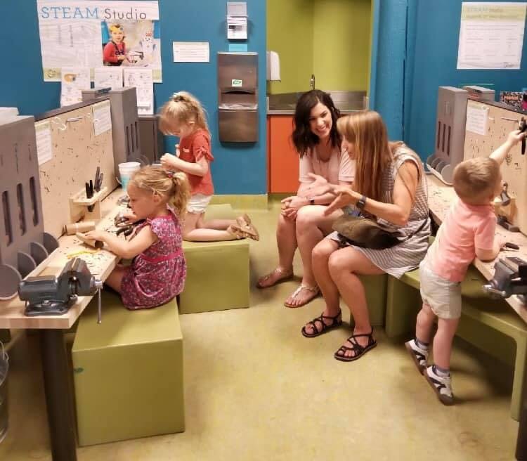 Adults and children in a classroom with workbenches
