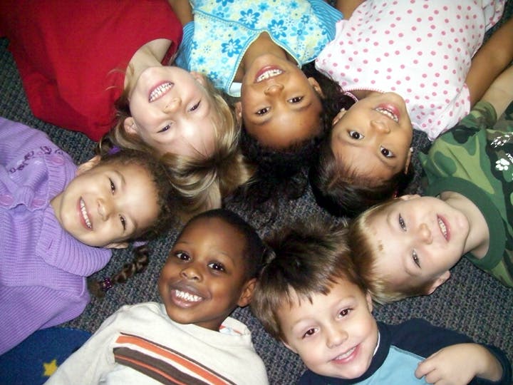 Seven children lying in a circle looking up