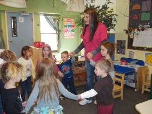 Adult and children holding hands in a circle in a classroom