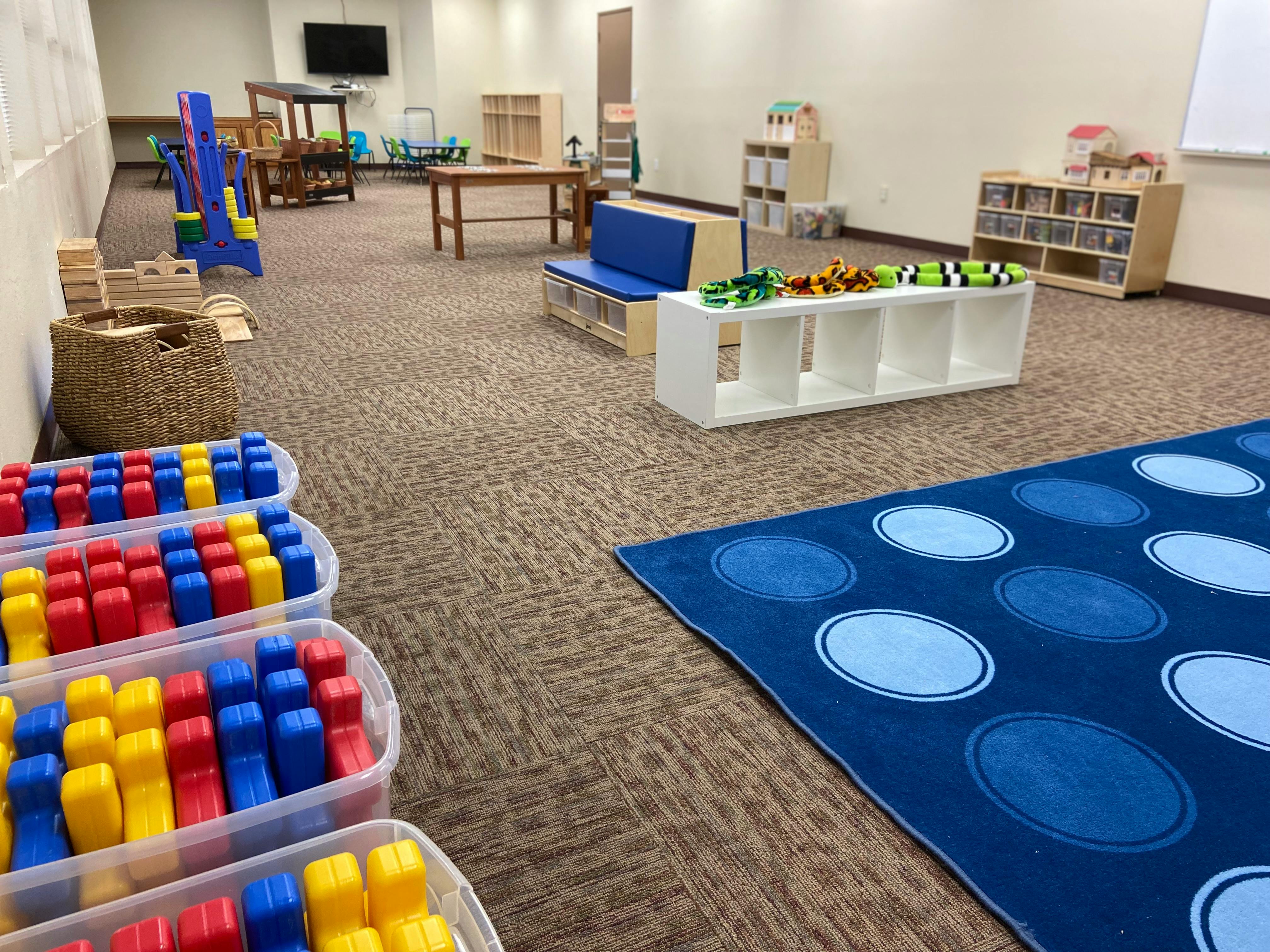 Playroom with colorful blocks, blue rug, and various furniture