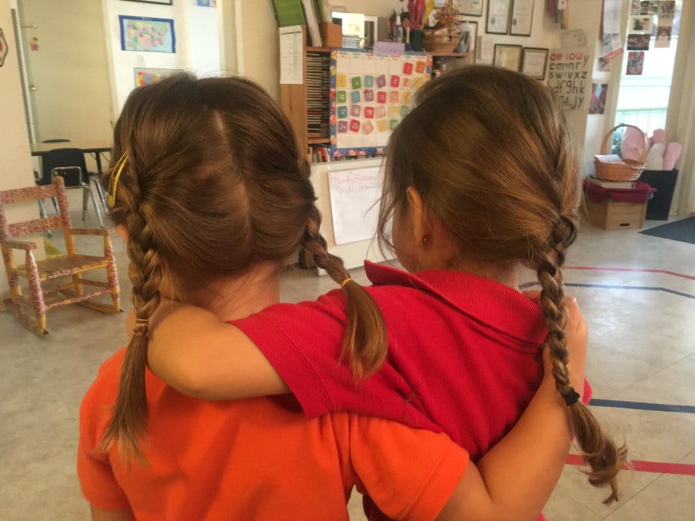 Two children with braided hair, one with arm around the other