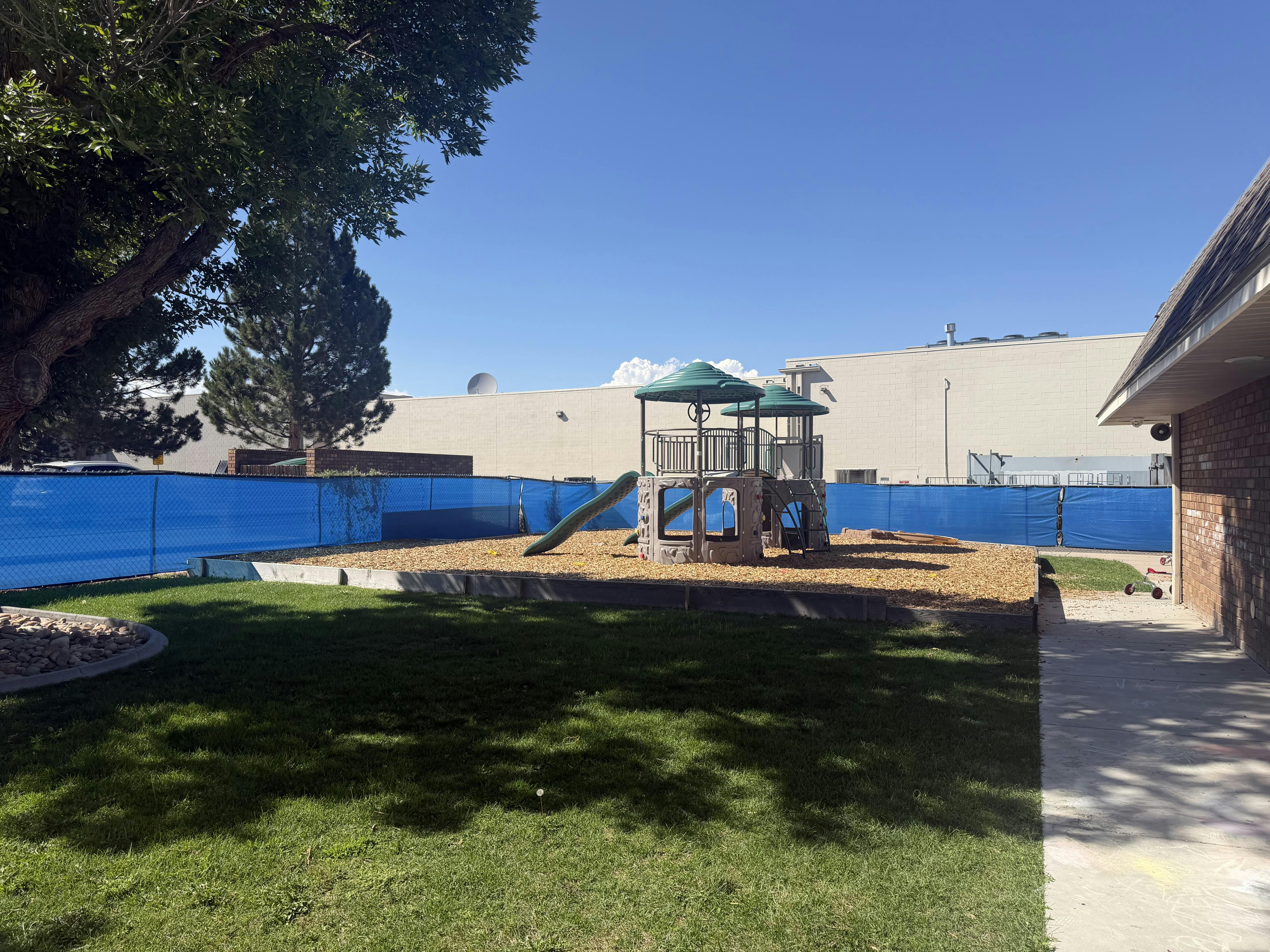 Childrens play structure on wood chips in a fenced yard