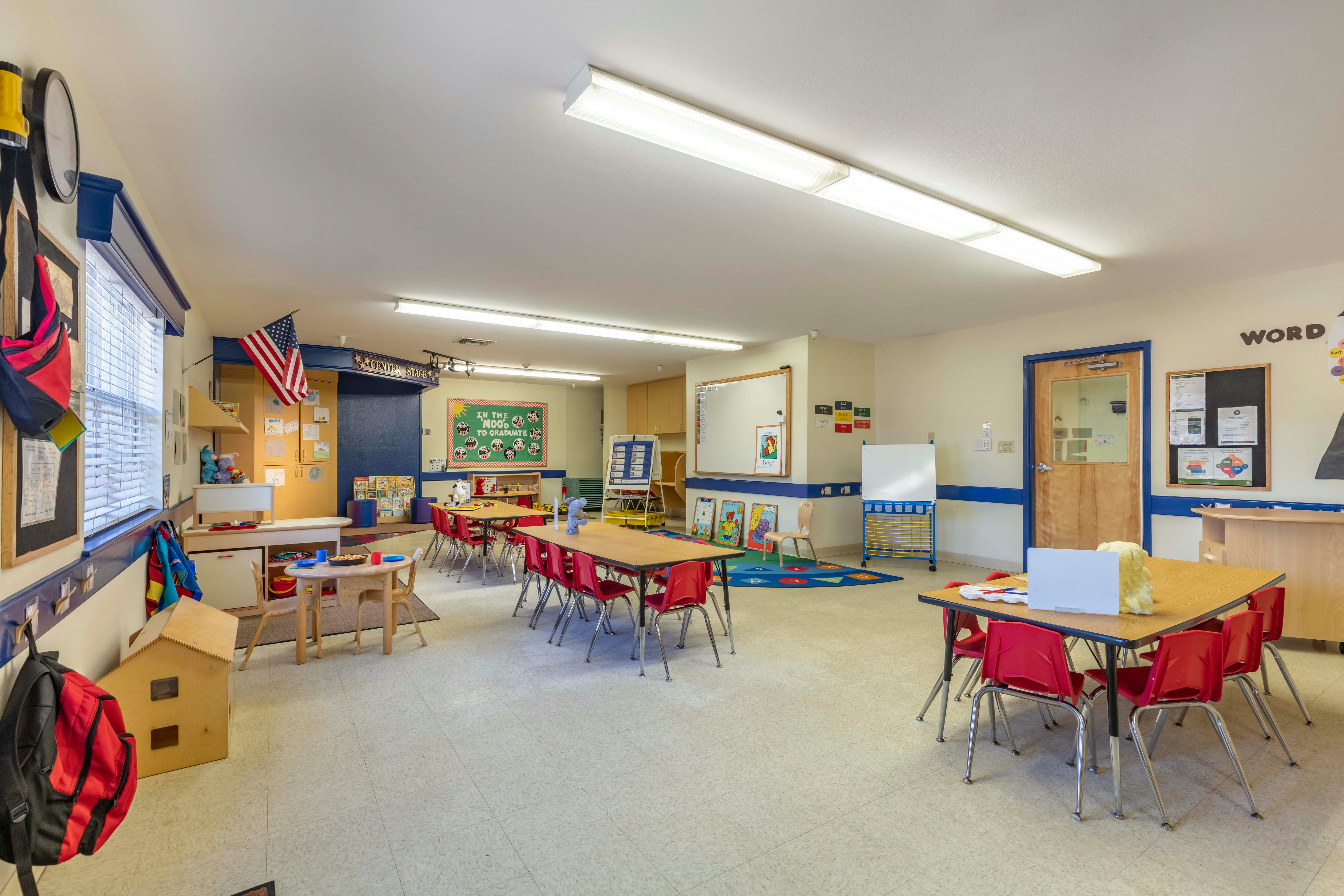 Classroom with small tables and chairs, activity centers, and bulletin boards