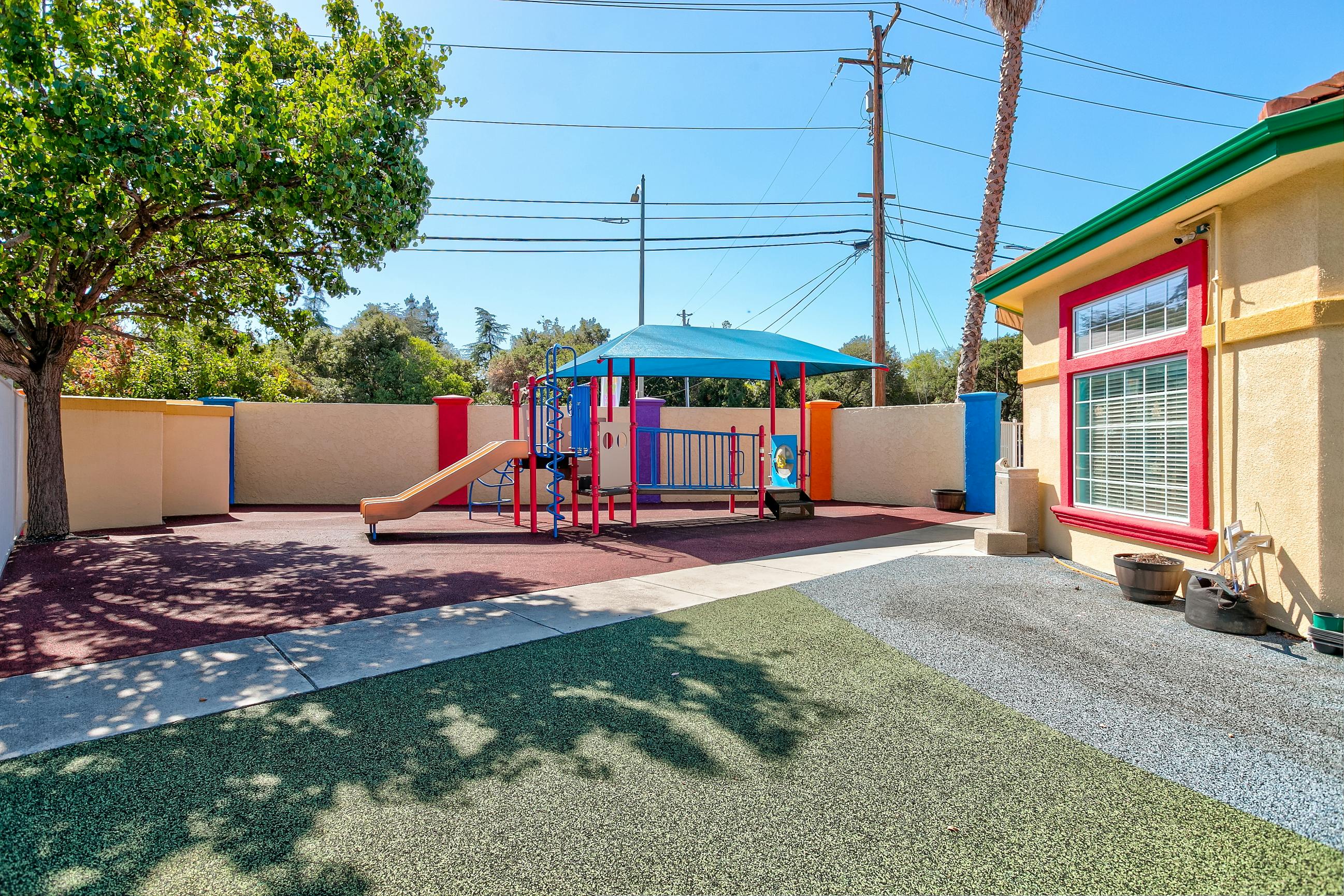 Playground structure with a slide under a blue canopy