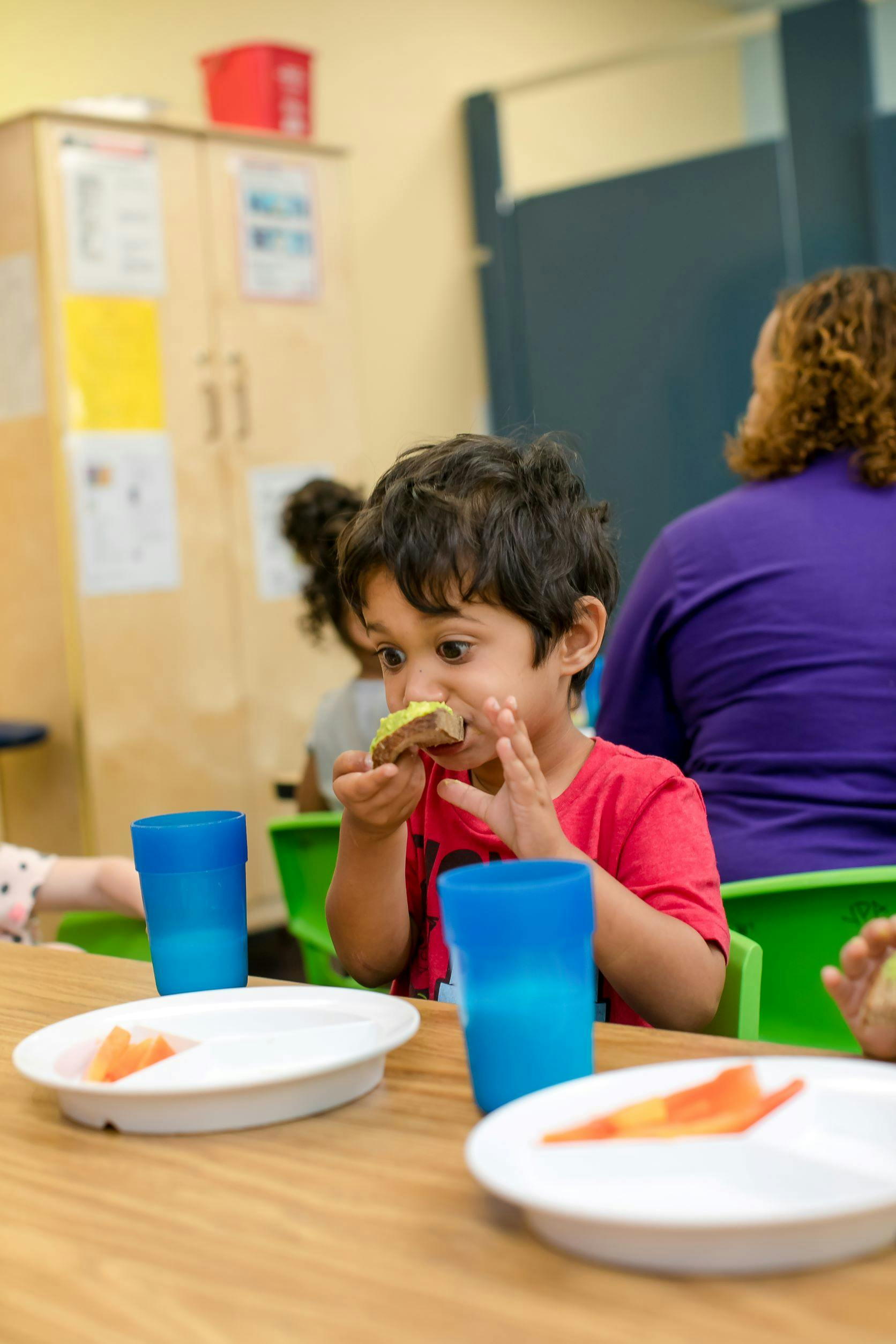 Child eating a snack at a table with blue cups and plates