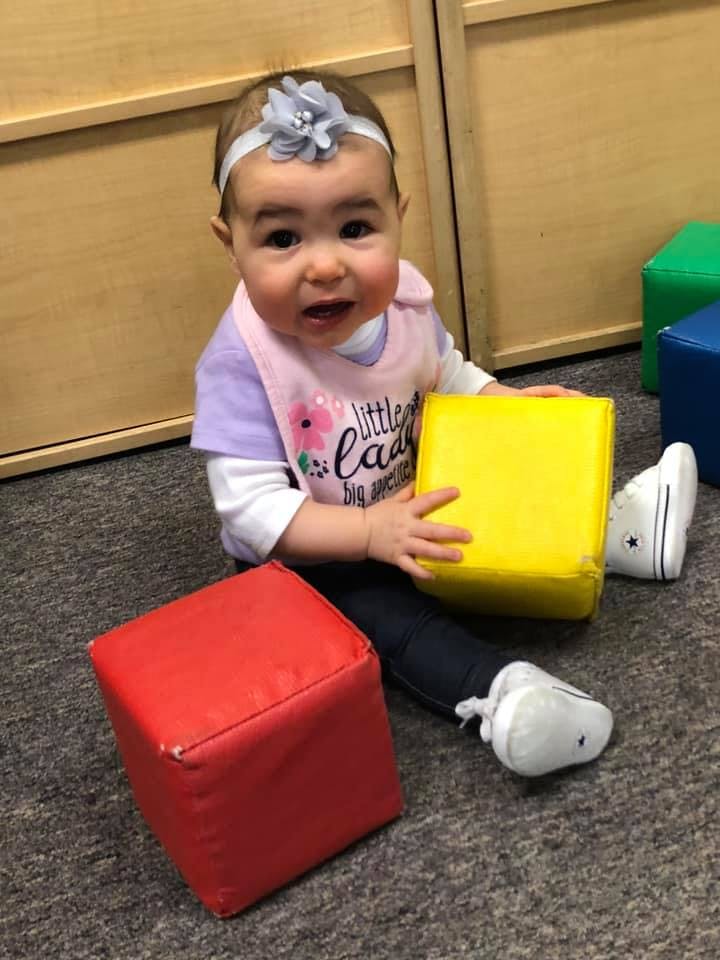 Child sitting on floor with red and yellow blocks