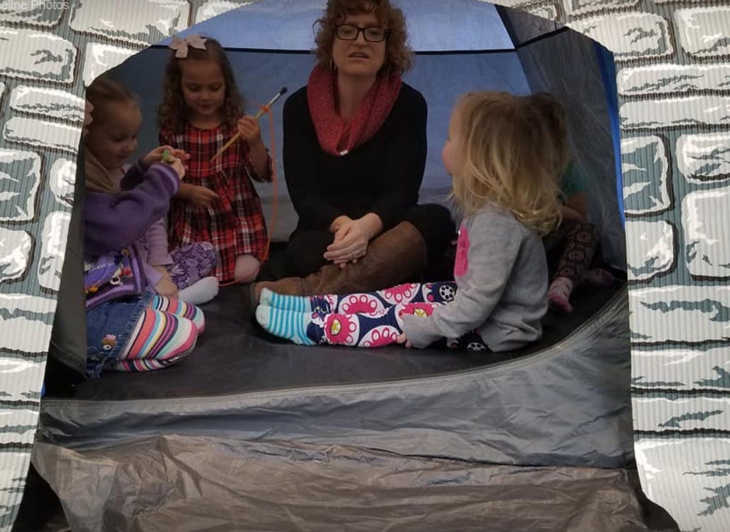 Adult and children sitting inside a tent