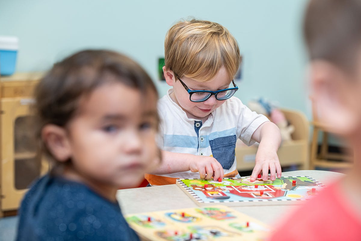 Child in glasses playing a board game at a table