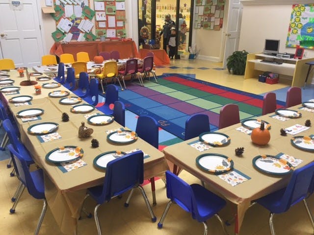Classroom with tables set for a meal and a colorful play mat