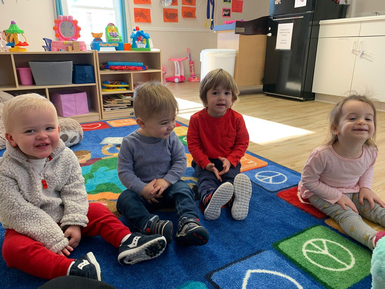 Four children sitting on a rug in a classroom