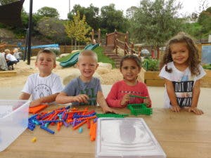 Four children at a table with toys in a play area
