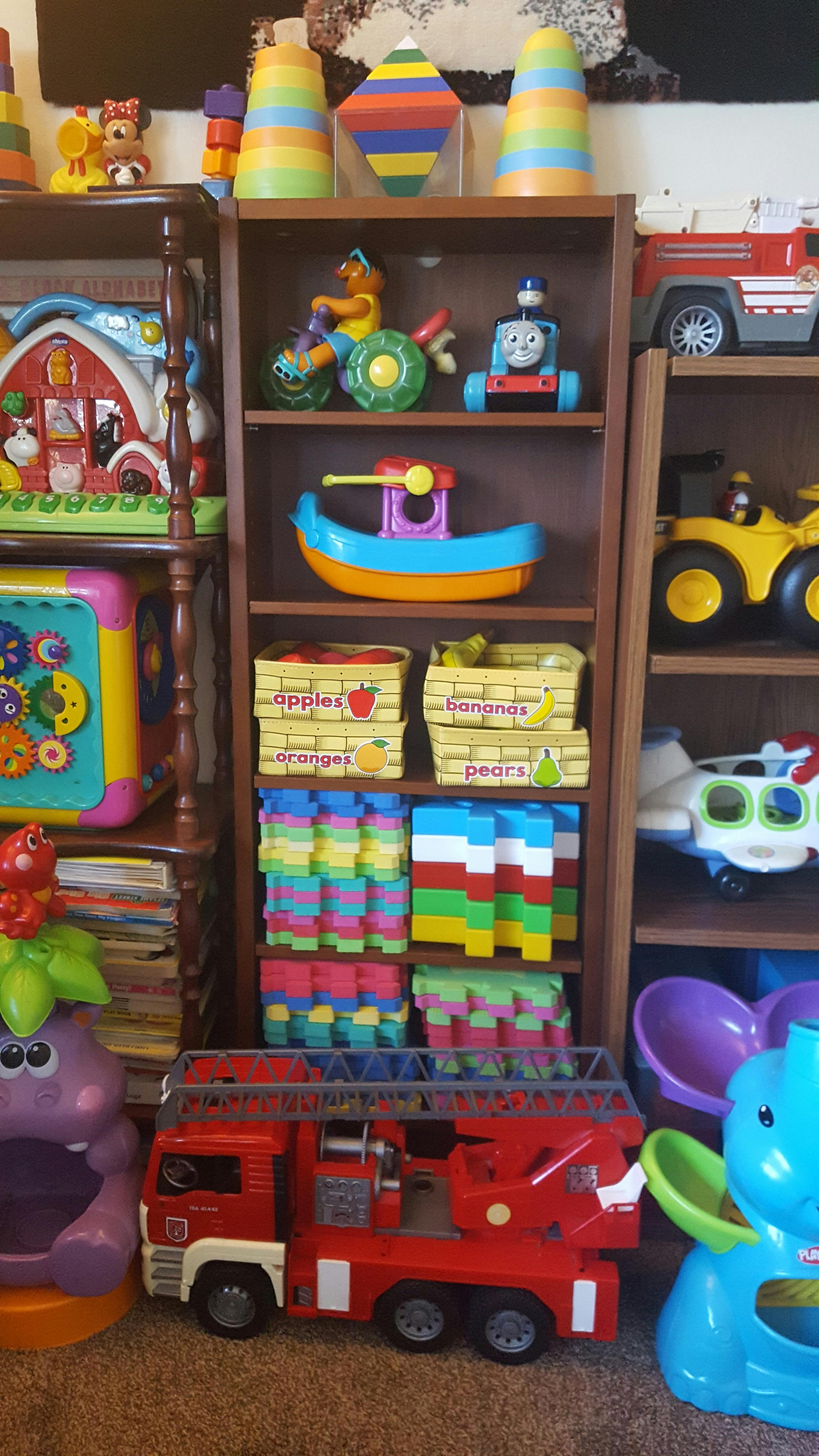 Shelves filled with various colorful toys, including blocks, vehicles, and fruit baskets