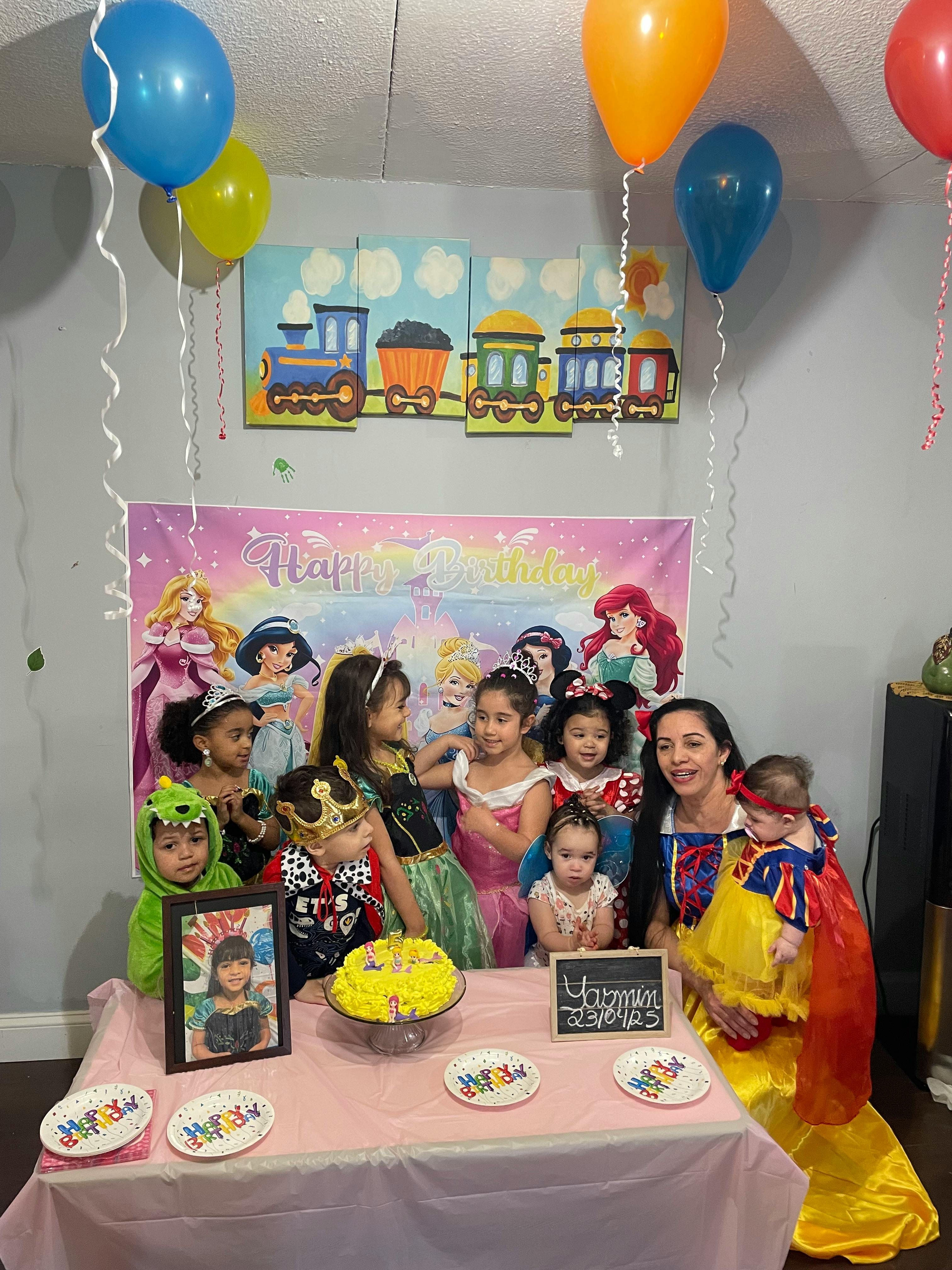 Group of people and children in costumes around a table with a cake
