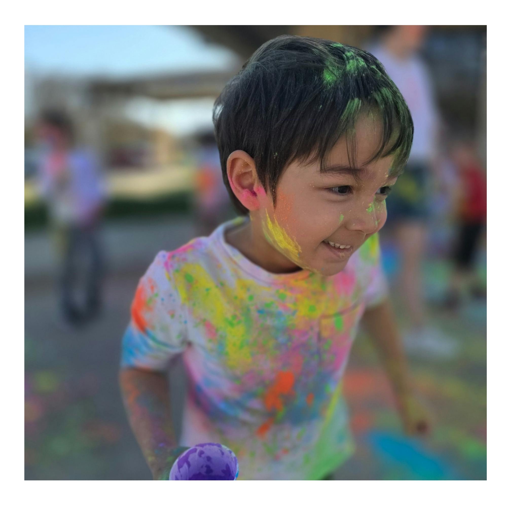 Child covered in colorful powder outdoors