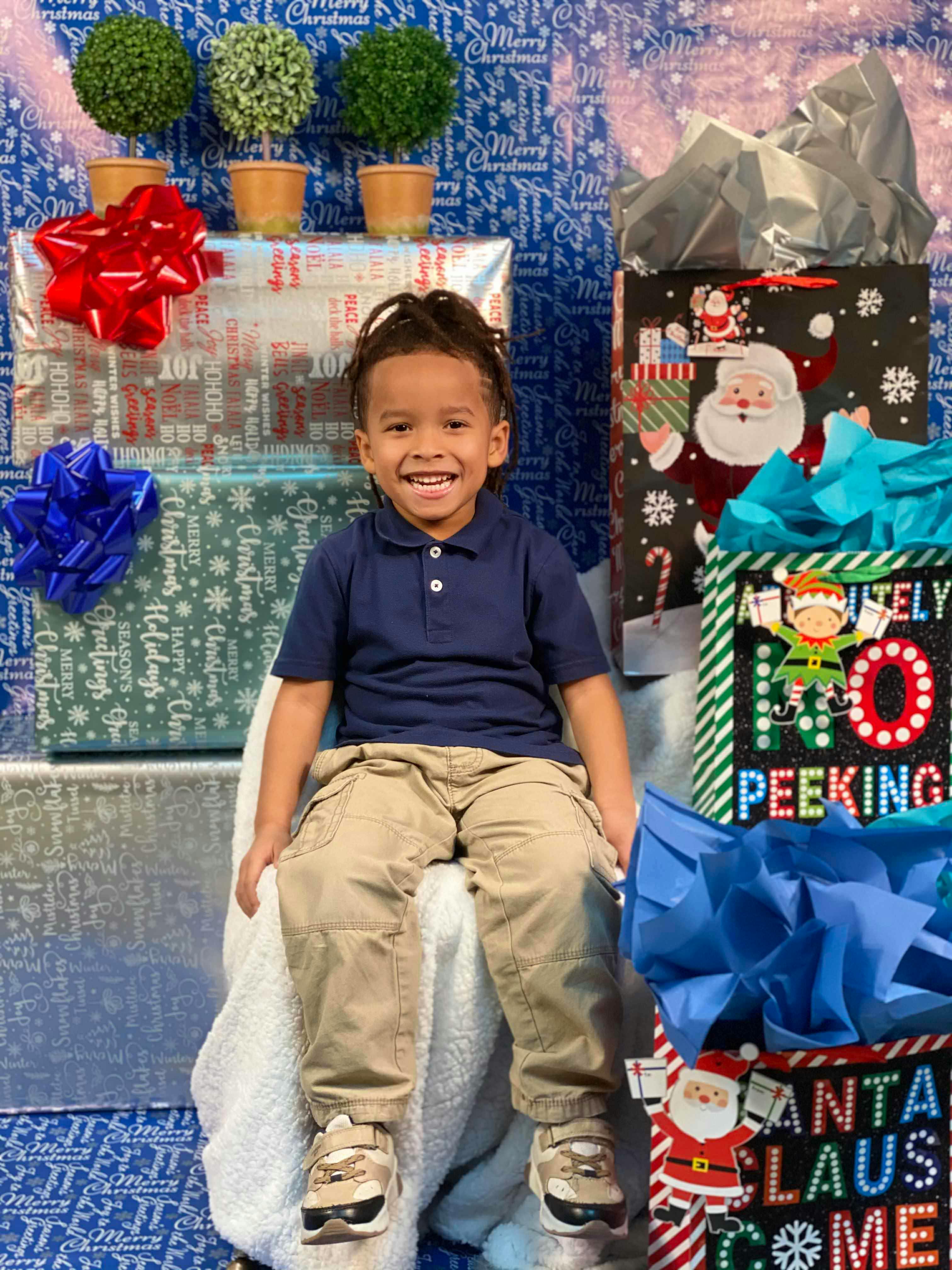 Child sitting among wrapped gifts and gift bags