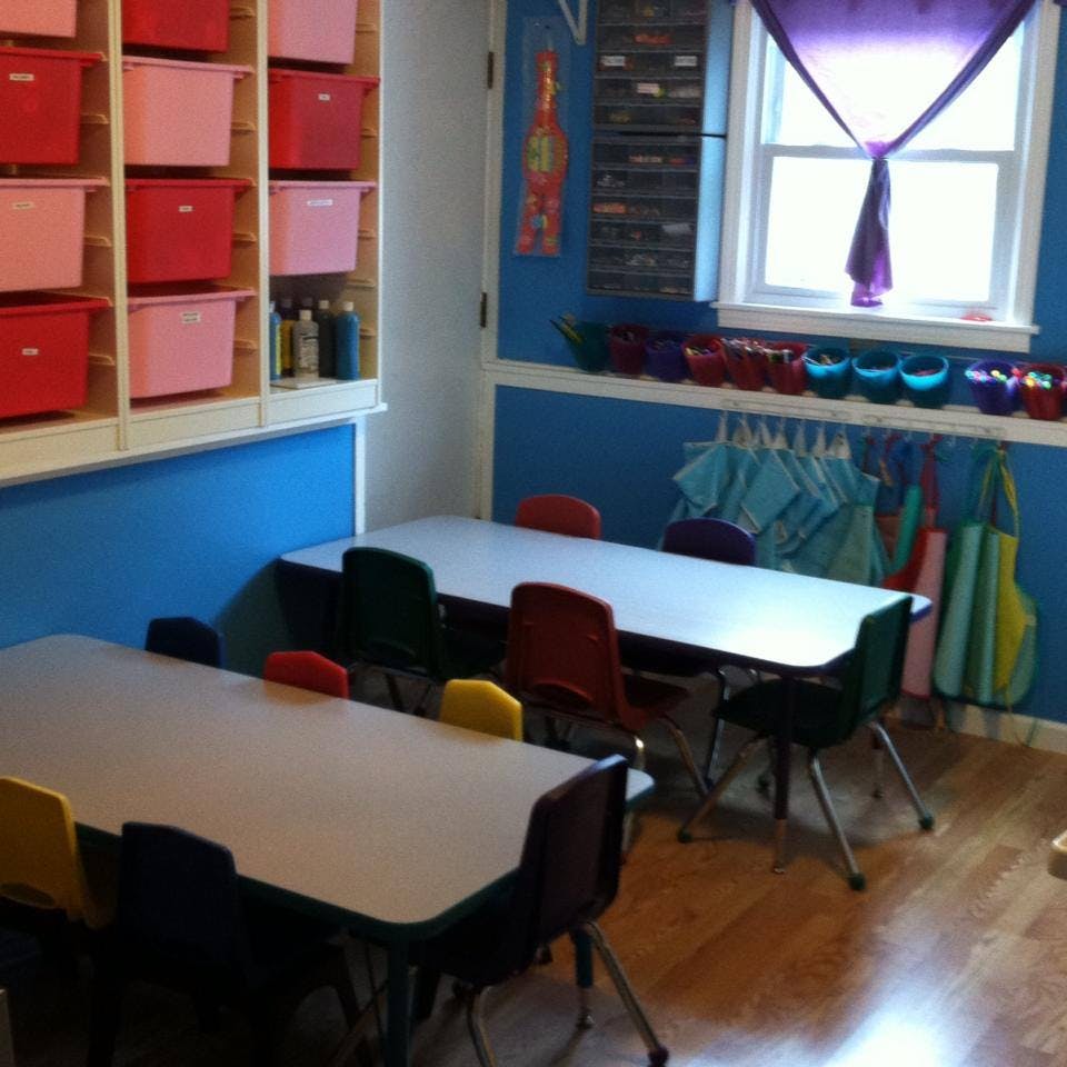 Classroom with tables and chairs, storage shelves, and a window