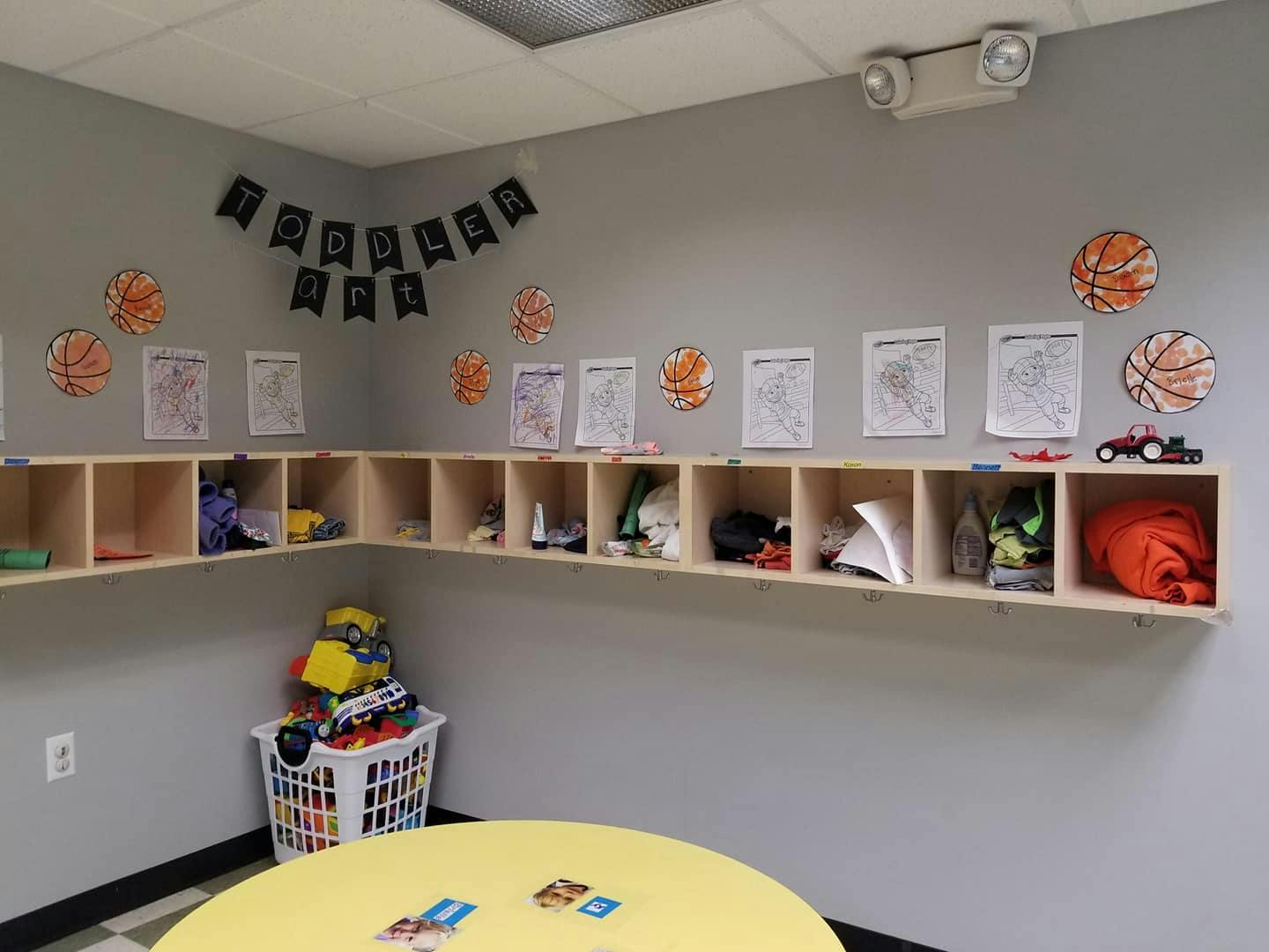 Classroom corner with cubbies, a laundry basket of toys, and a yellow table