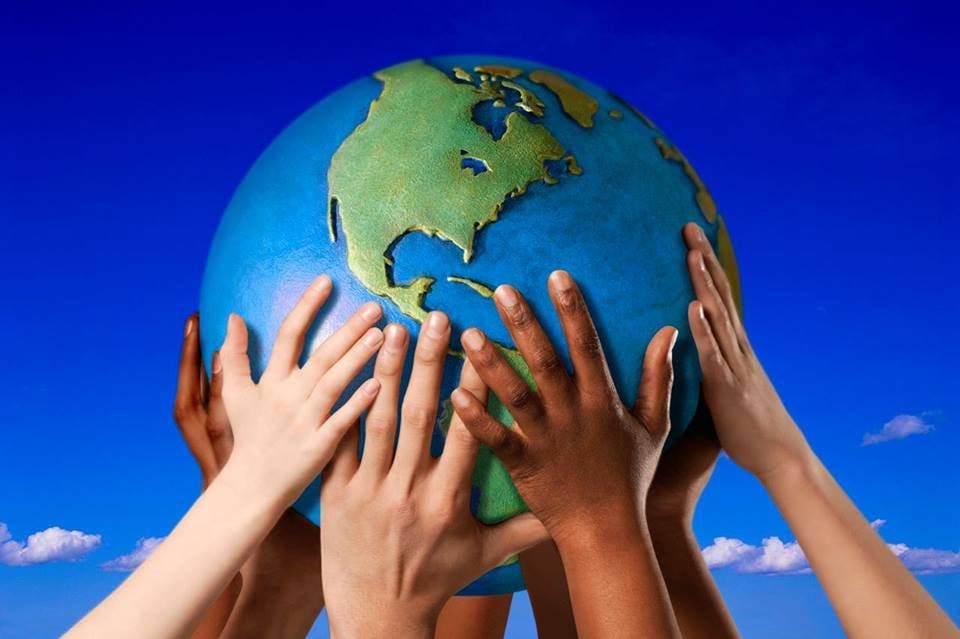 Multiple hands of different skin tones holding a globe