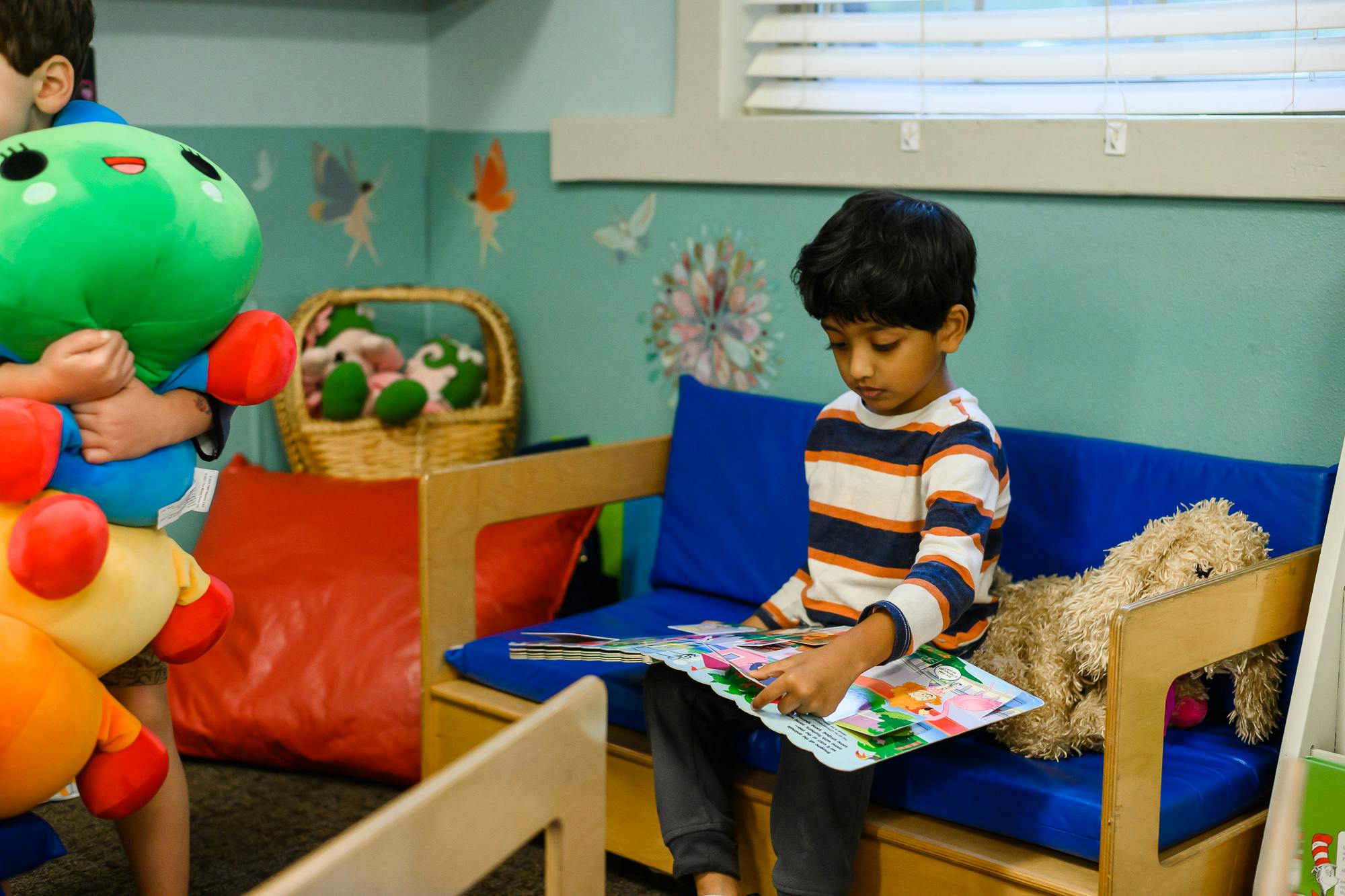 Child sitting on a blue couch reading a book