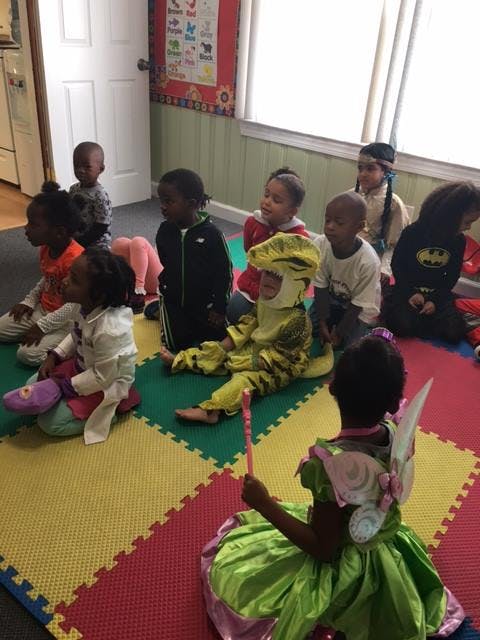 Children in costumes sitting on a colorful mat