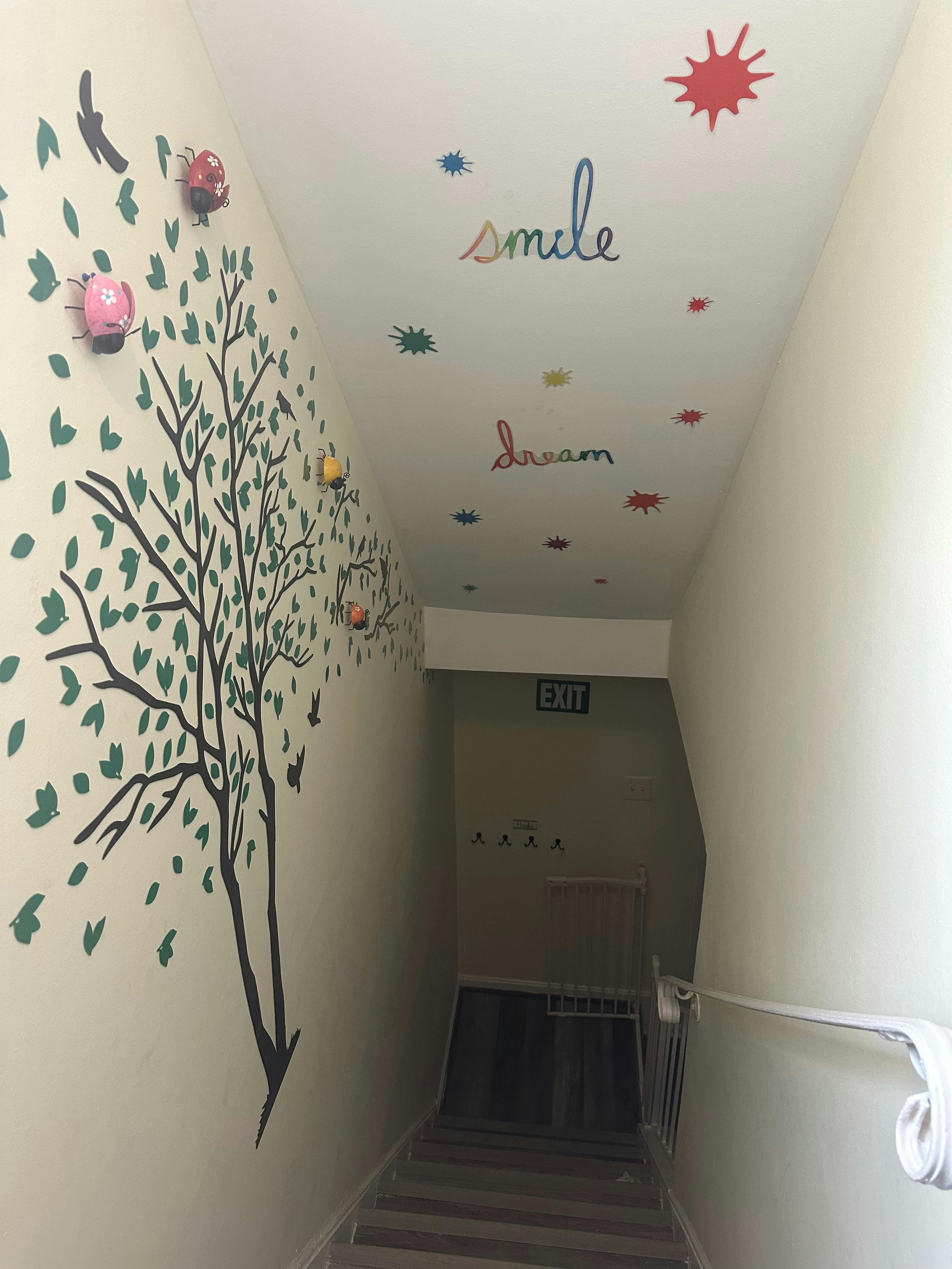 Stairwell with tree mural on wall and words "smile" and "dream" on ceiling