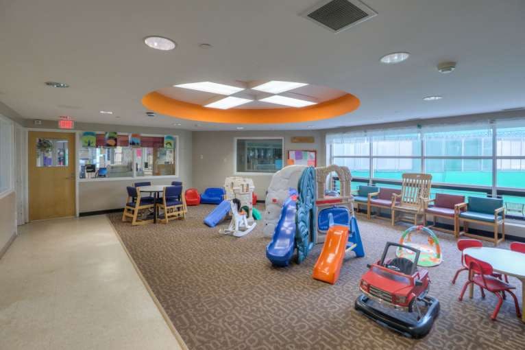 Indoor play area with slides, rocking horses, and small tables