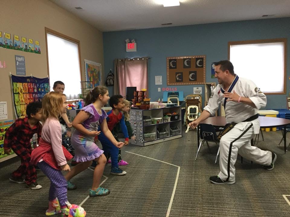 Adult in martial arts uniform teaching children in a classroom