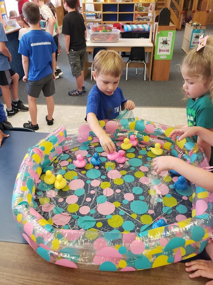 Two children playing with rubber ducks in an inflatable pool