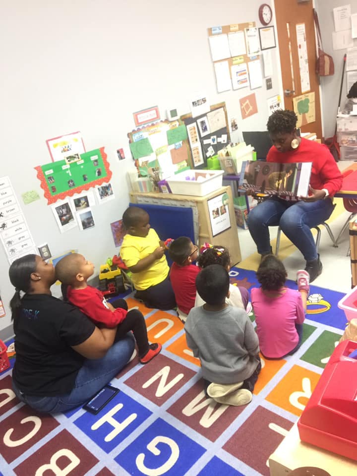 Adult reading a book to children in a classroom