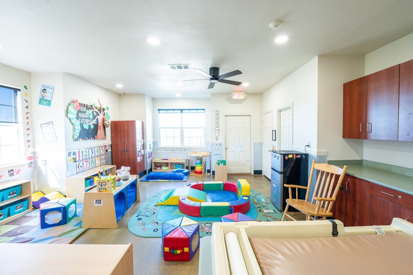 Childcare classroom with toys and a soft play structure on the floor