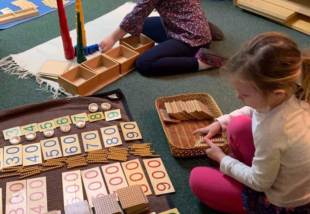 Two children on the floor playing with math manipulatives