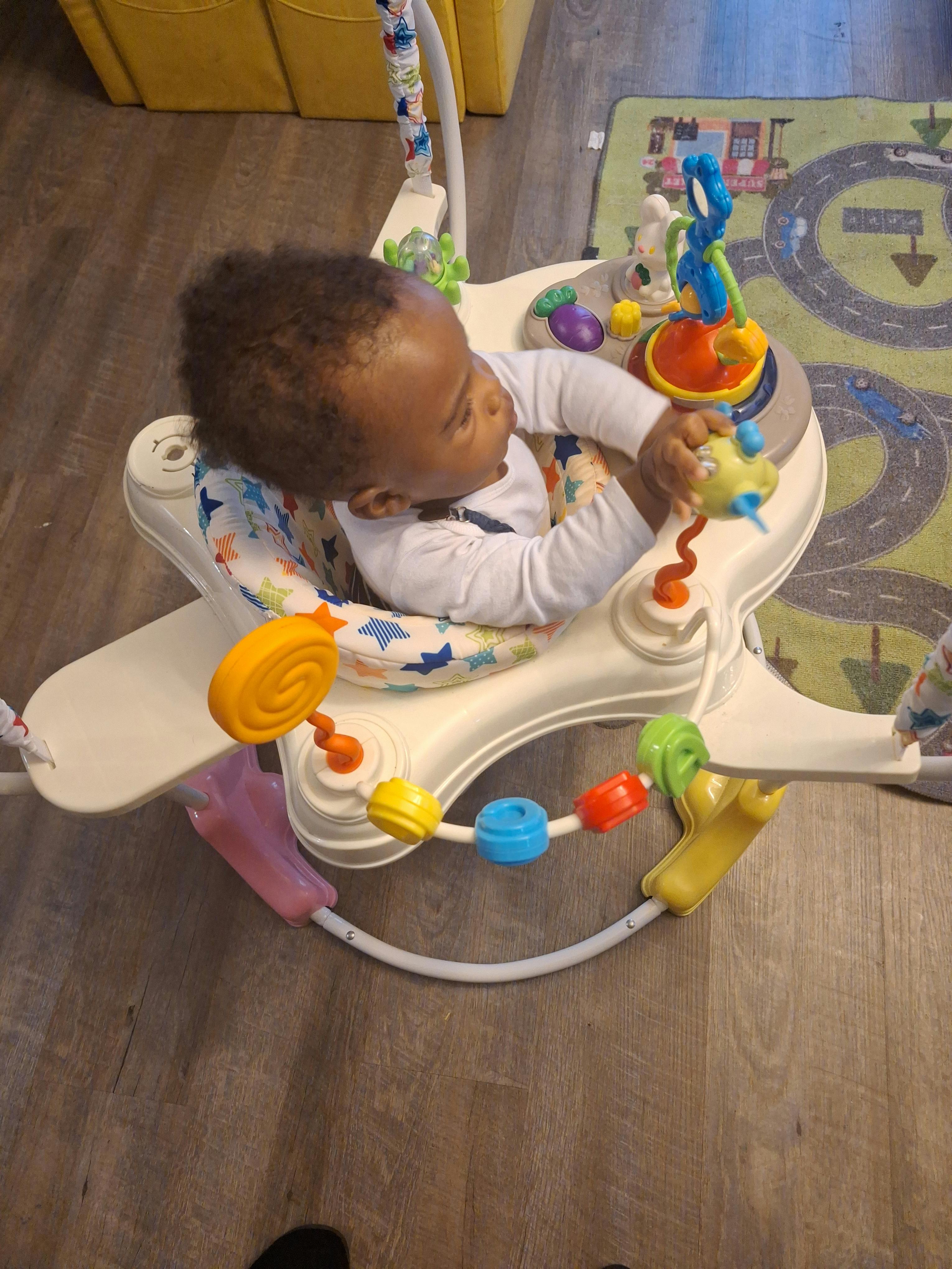 Child in a baby bouncer playing with toys