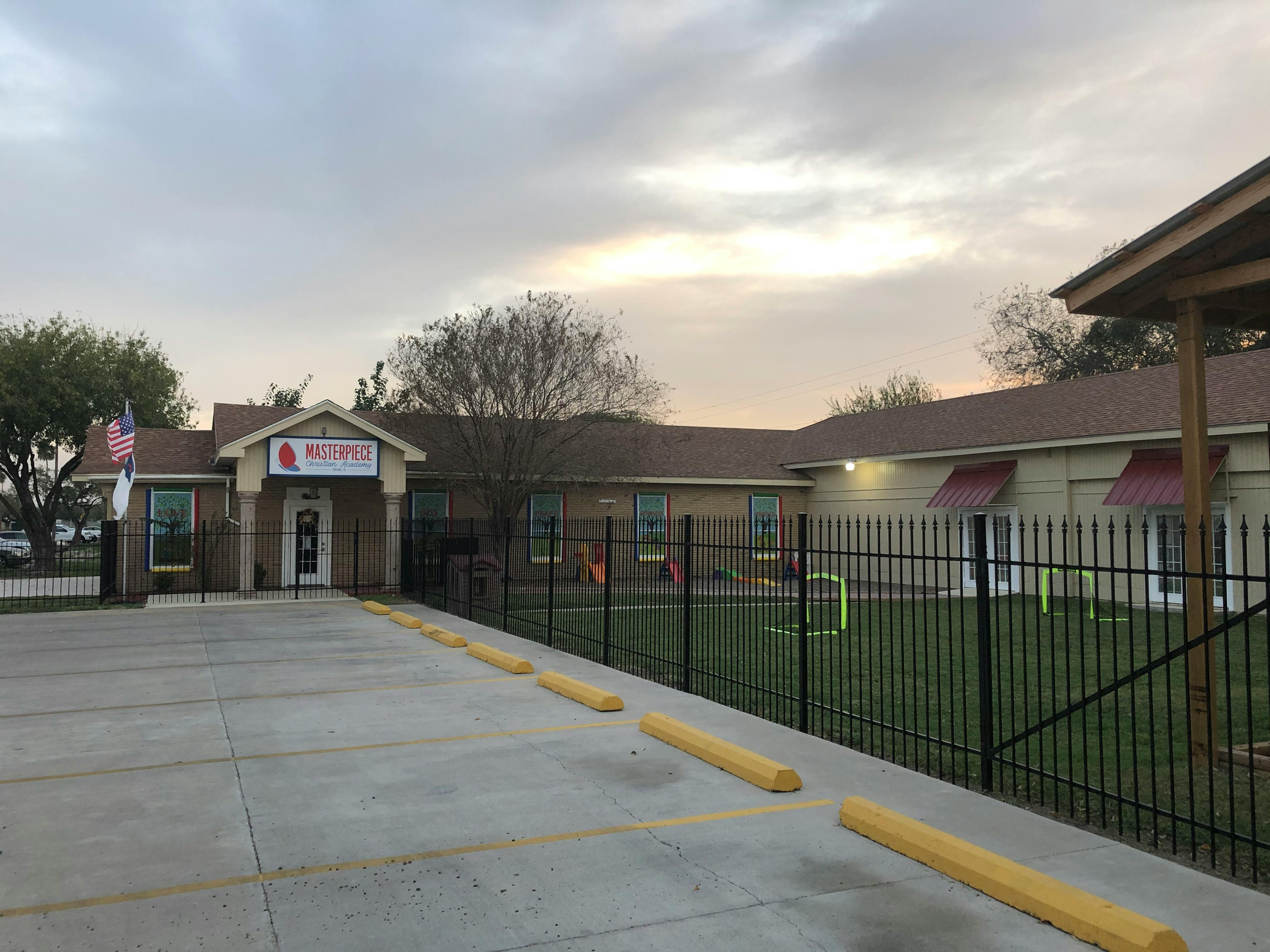 Building with a fenced-in grassy area and a parking lot
