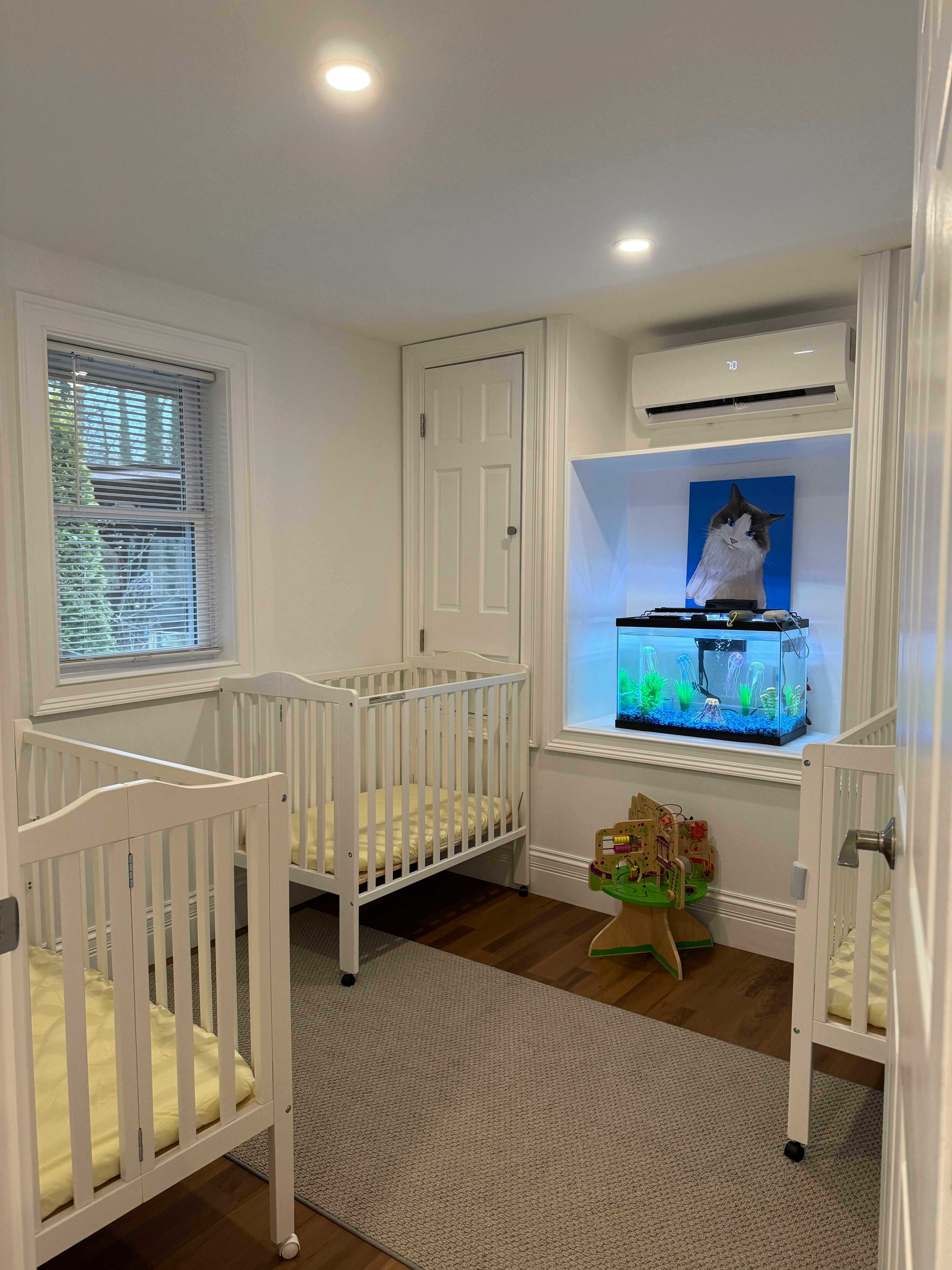 Room with two cribs and a fish tank